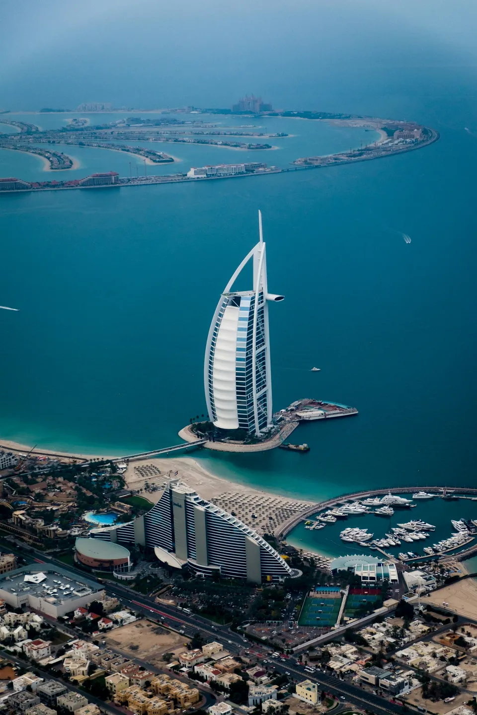 Aerial view of a sail-shaped Dubai hotel beside the sea