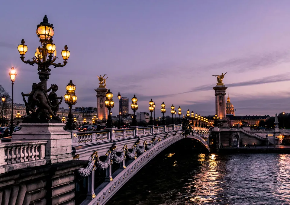 Ornate bridge and street lamps over a river at dusk