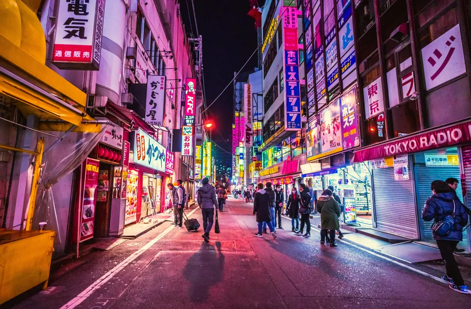 Pedestrians on a neon-lit Japanese shopping street at night