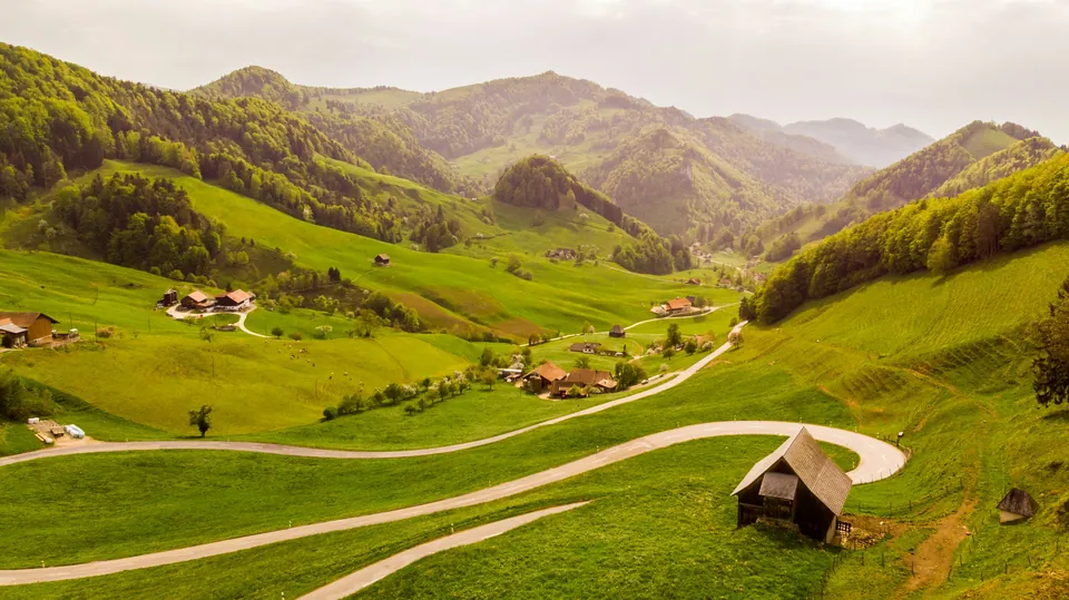 Green Swiss valley with winding paths, villages and mountains