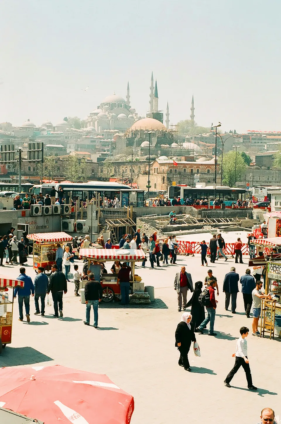 Pedestrians in an Istanbul square with a mosque in the distance